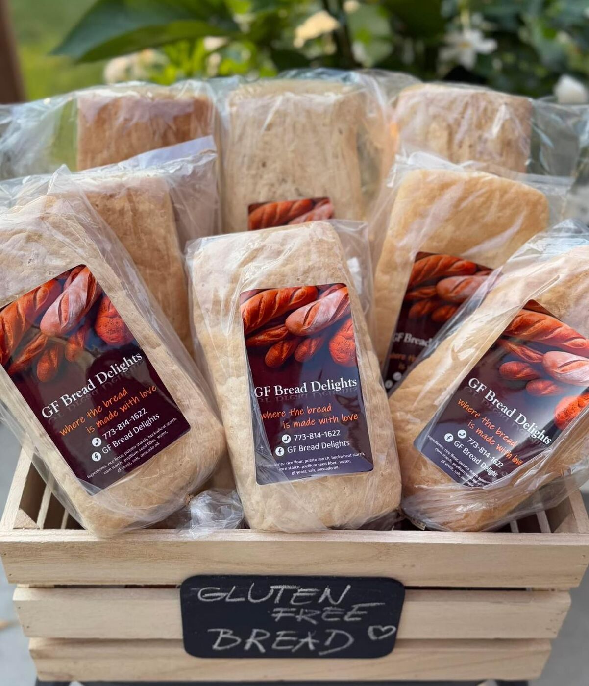 Crate of packaged gluten-free loaves with a chalkboard sign reading gluten free bread