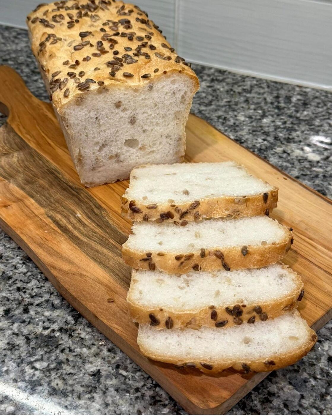 Seeded gluten-free loaf cut open showing a soft crumb