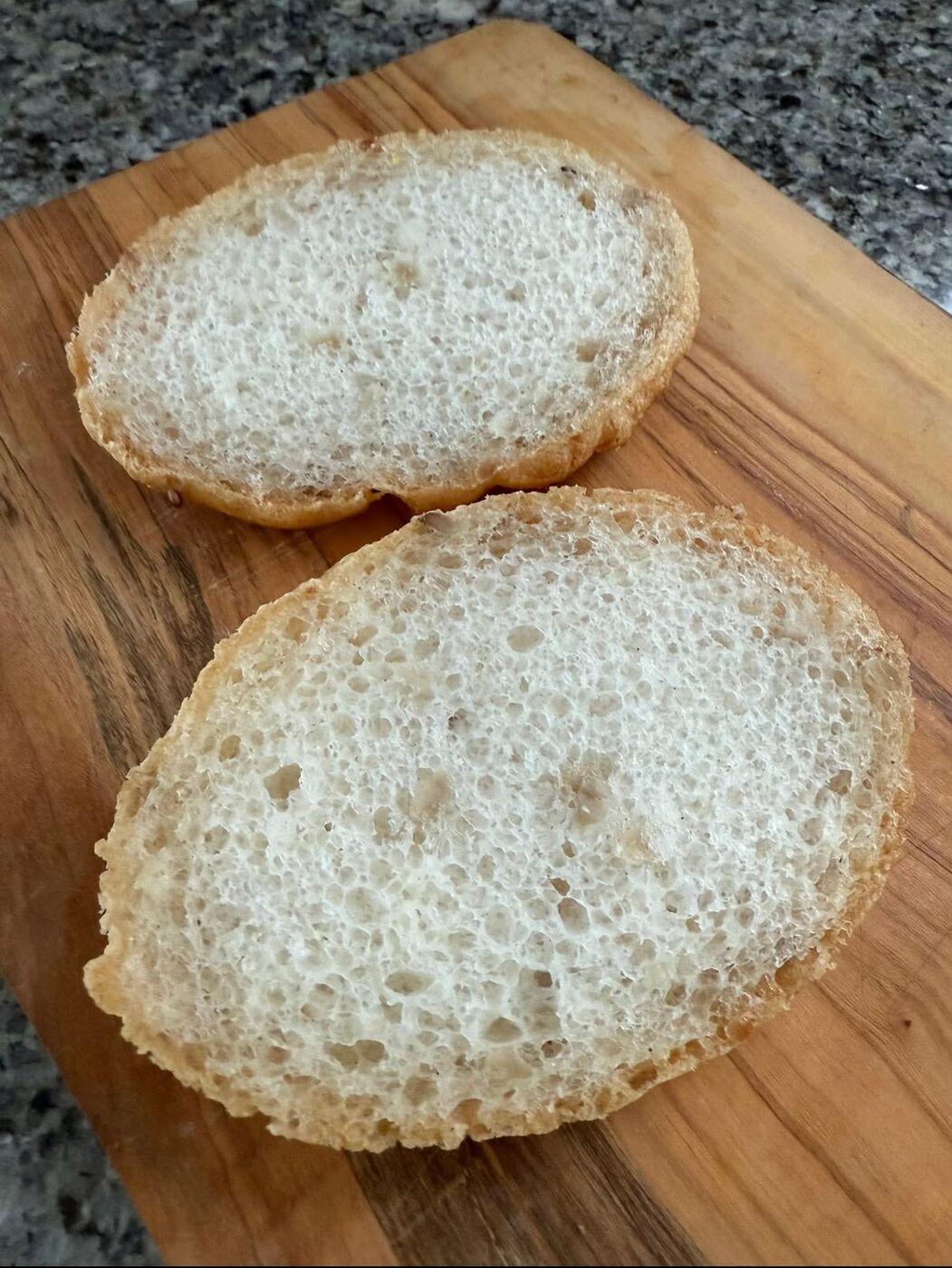 A gluten-free roll cut in half showing an airy crumb